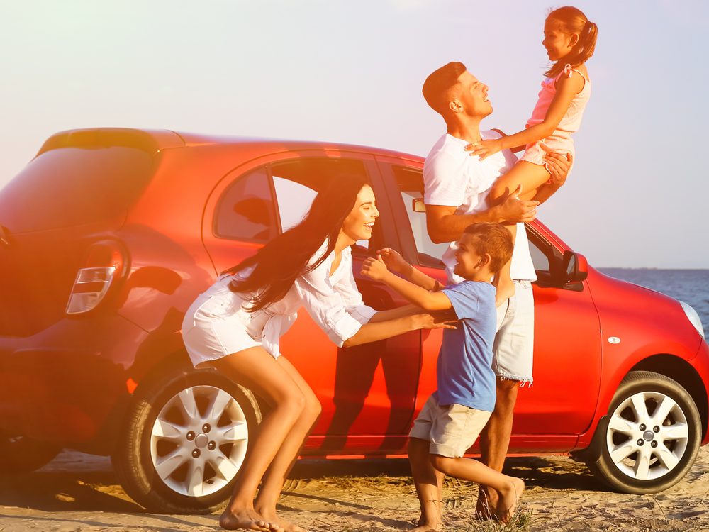 Familia junto a un coche rojo que representa el Plan Renueva de Automóviles CALCU en Málaga
