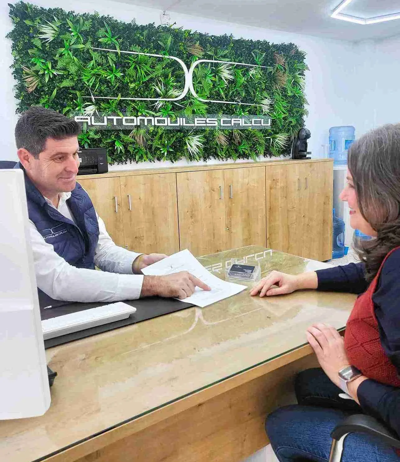 Jose, de Automóviles CALCU, explica un documento a una clienta durante una reunión de asesoramiento en Málaga.